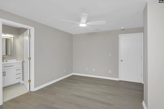 unfurnished bedroom with wood finished floors, baseboards, connected bathroom, and ceiling fan