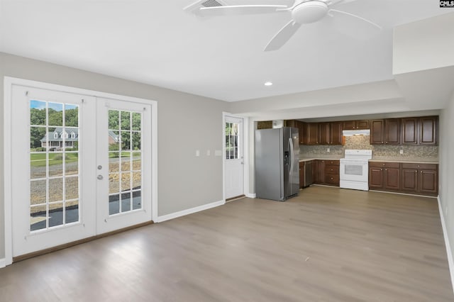 kitchen with stainless steel fridge with ice dispenser, white range with electric cooktop, under cabinet range hood, french doors, and light wood-style floors