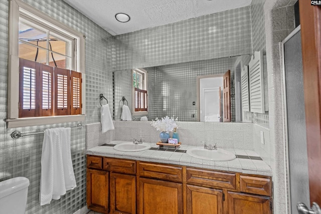 3040 Barnes Springs Rd, Columbia, SC 29204 - bathroom featuring toilet, tile walls, a stall shower, a textured ceiling, and double vanity