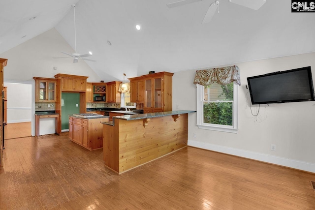 2203 Lincoln St, Columbia, SC 29201 - kitchen with a ceiling fan, brown cabinets, glass insert cabinets, a peninsula, and decorative backsplash