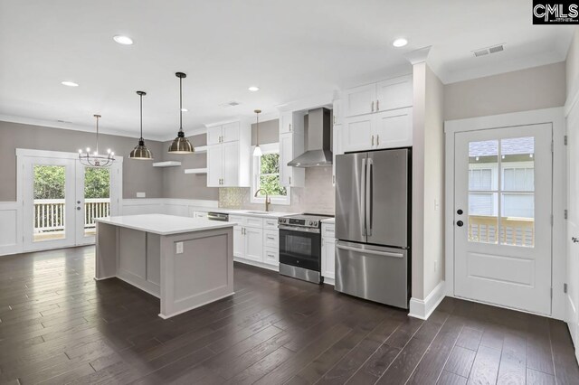 1409 Woodrow St, Columbia, SC 29205 - kitchen with stainless steel appliances, wall chimney range hood, light countertops, white cabinetry, and a chandelier