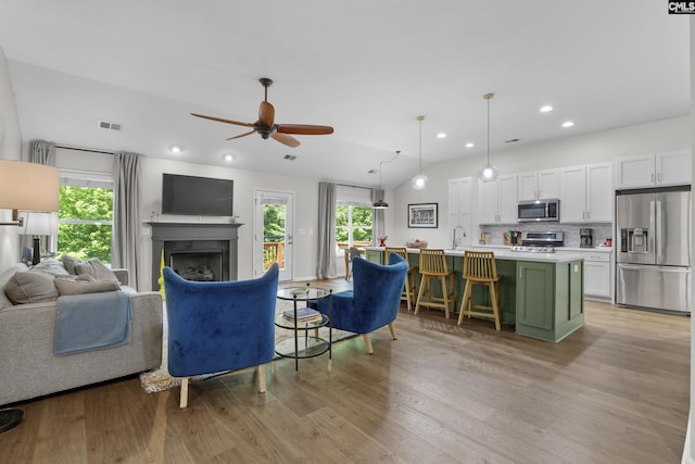 living room with light wood-style flooring, a fireplace, a ceiling fan, and recessed lighting