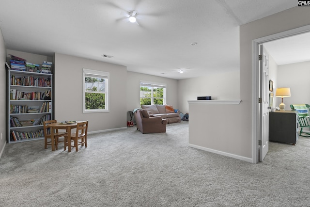 carpeted living area with baseboards and a ceiling fan