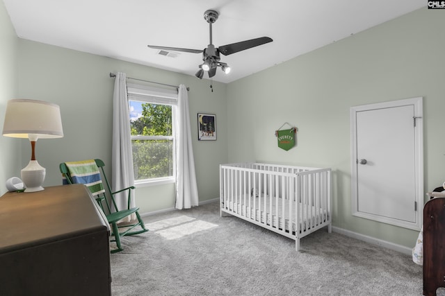 bedroom featuring carpet flooring, a nursery area, baseboards, and ceiling fan