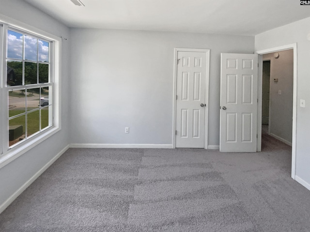 unfurnished bedroom with carpet flooring, multiple windows, and baseboards