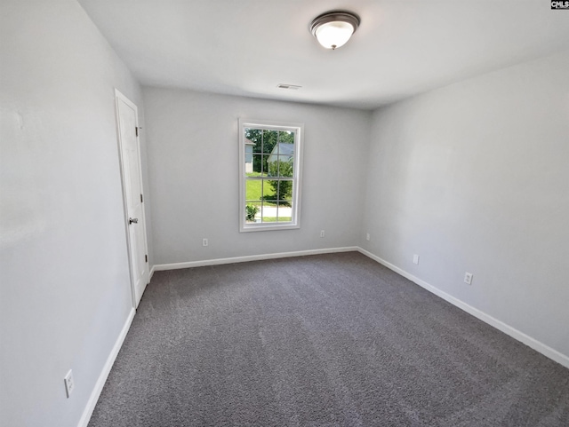 unfurnished room with dark carpet and baseboards