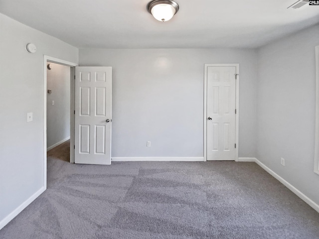 carpeted empty room featuring baseboards and a smoke detector