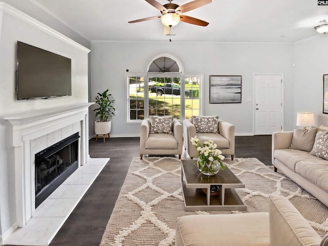 living area with ceiling fan, baseboards, a fireplace, crown molding, and wood finished floors