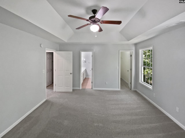 unfurnished bedroom featuring a raised ceiling, carpet flooring, and baseboards