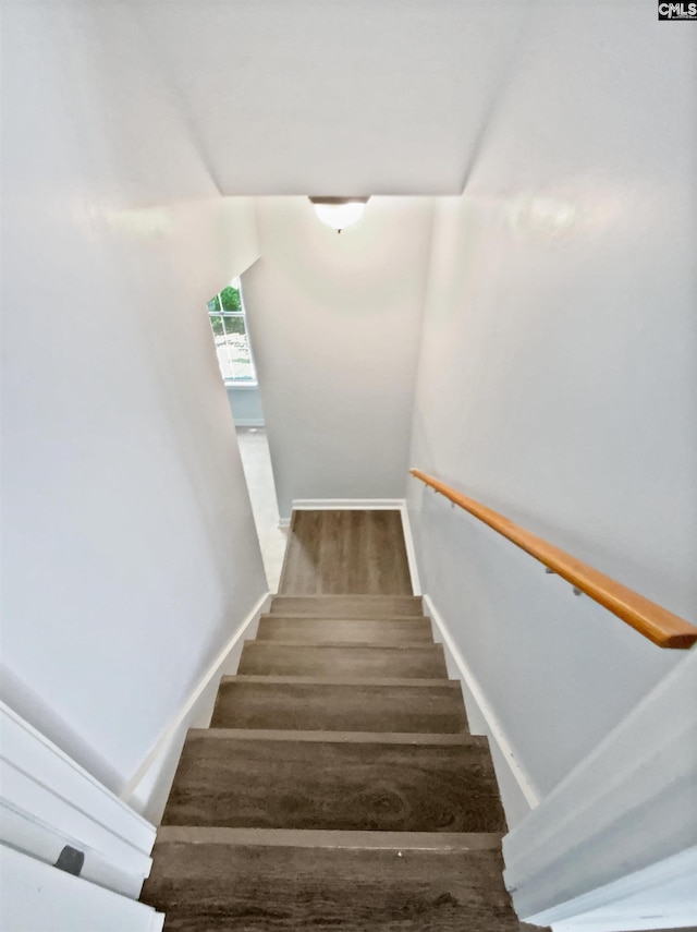 staircase featuring wood finished floors and baseboards
