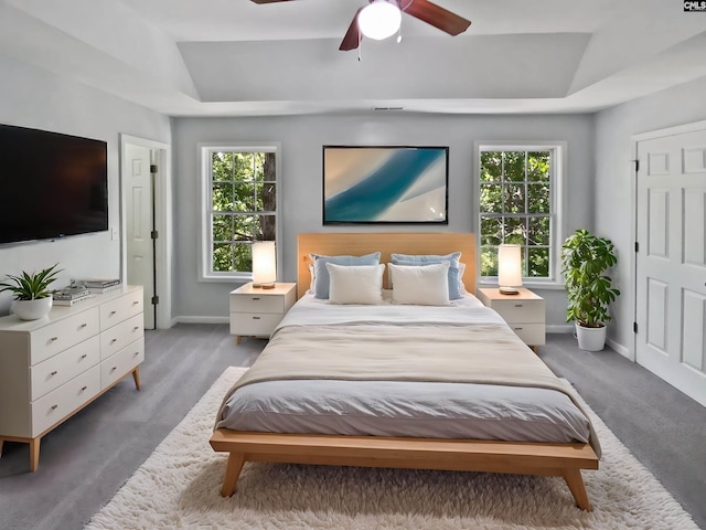 bedroom featuring a tray ceiling, baseboards, and ceiling fan