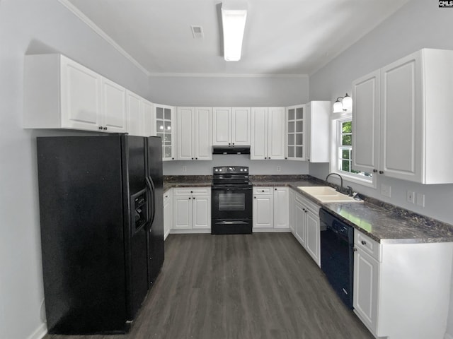 kitchen with black appliances, a sink, under cabinet range hood, dark wood finished floors, and glass insert cabinets
