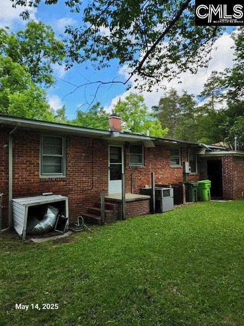 1128 Omega Dr, Columbia, SC 29223 - back of house featuring a lawn, central AC unit, brick siding, and a chimney