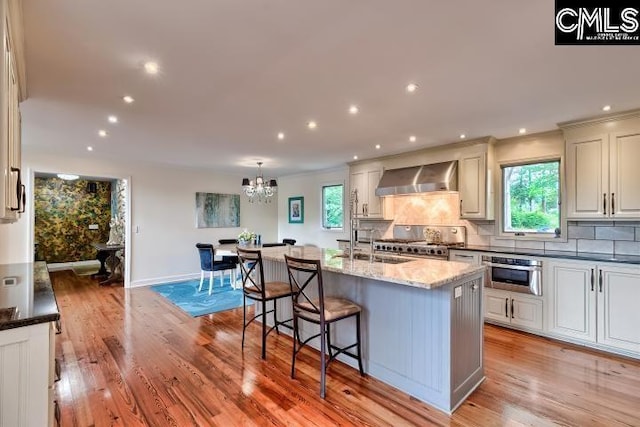 kitchen featuring wall chimney range hood, range, decorative backsplash, healthy amount of natural light, and recessed lighting