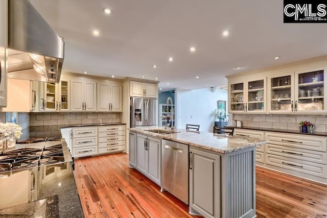 kitchen featuring appliances with stainless steel finishes, island range hood, a sink, backsplash, and recessed lighting