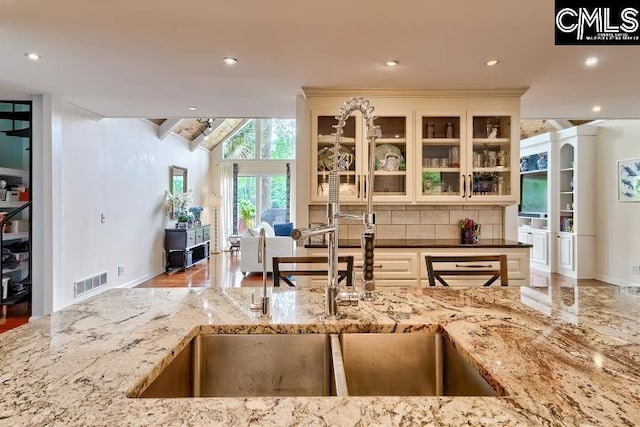 kitchen with light stone counters, a sink, tasteful backsplash, baseboards, and recessed lighting