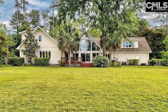 rear view of property with a deck, a yard, and cooling unit
