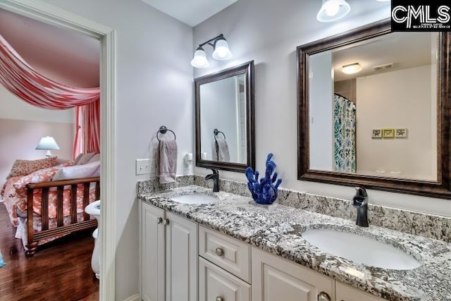 full bathroom with wood finished floors, double vanity, and toilet
