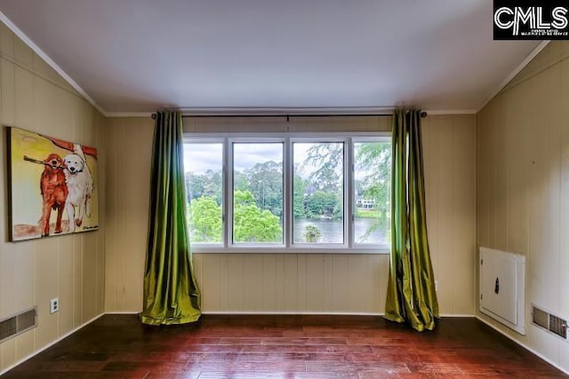 spare room with wood finished floors, healthy amount of natural light, and ornamental molding