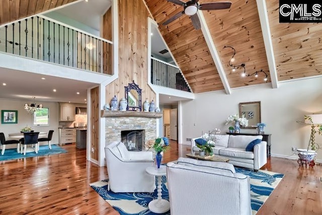 living room with high vaulted ceiling, wood finished floors, wooden ceiling, a stone fireplace, and ceiling fan