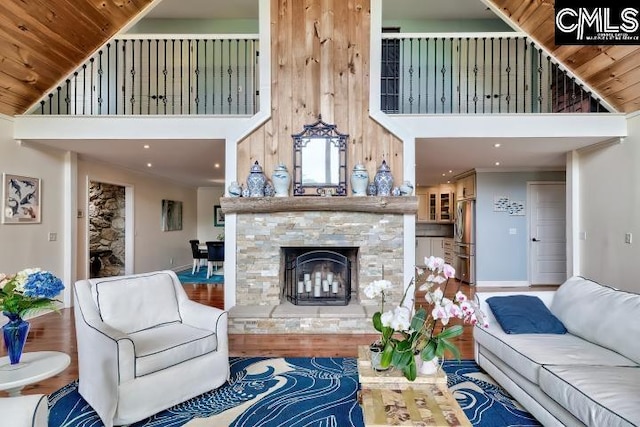 living area featuring a high ceiling, a fireplace, wood finished floors, and baseboards