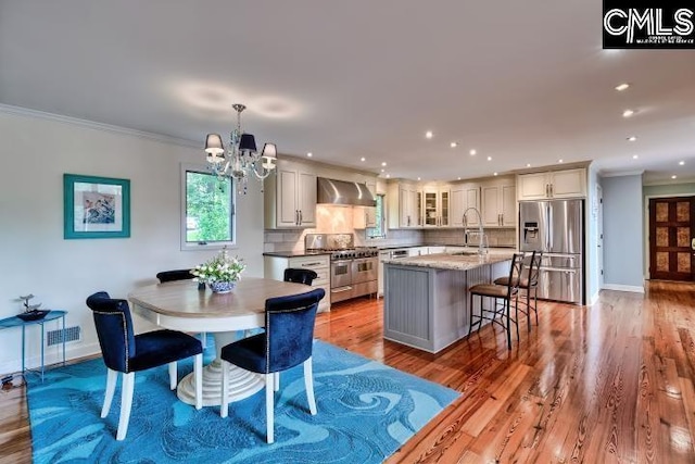 dining room featuring ornamental molding, a chandelier, baseboards, recessed lighting, and light wood-style flooring