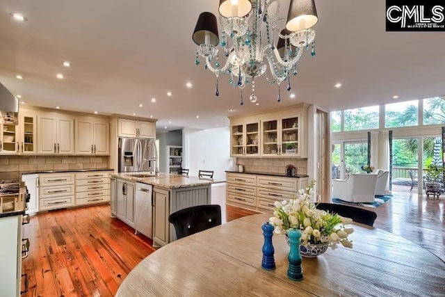 dining space featuring a chandelier, light wood-style floors, recessed lighting, and a wall of windows
