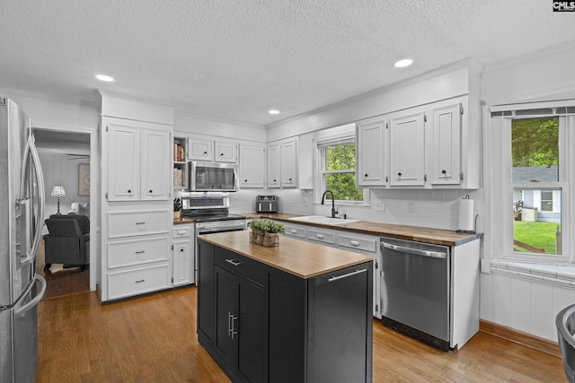kitchen featuring wood counters, stainless steel appliances, a sink, dark cabinetry, and white cabinetry