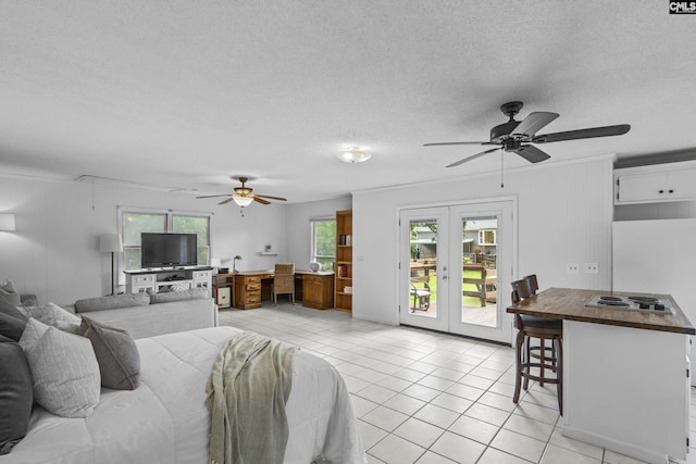 bedroom with french doors, an office area, access to exterior, a textured ceiling, and light tile patterned flooring