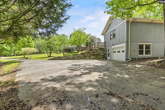 view of home's exterior with concrete driveway, a garage, and stairs