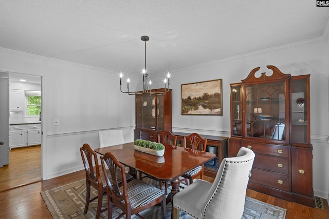 dining area featuring wood finished floors, ornamental molding, and a chandelier