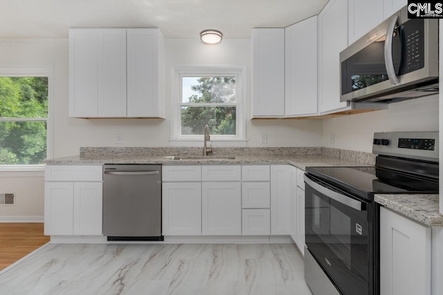3901 Overdale Dr, Columbia, SC 29223 - kitchen with appliances with stainless steel finishes, a sink, white cabinets, light stone counters, and crown molding