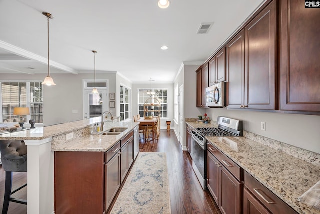 kitchen featuring appliances with stainless steel finishes, a sink, ornamental molding, dark wood-style flooring, and healthy amount of natural light