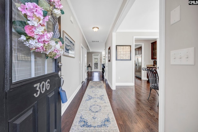 foyer featuring crown molding, dark wood-type flooring, and baseboards