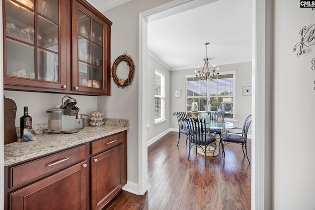 dining area featuring ornamental molding, dark wood finished floors, a chandelier, and baseboards
