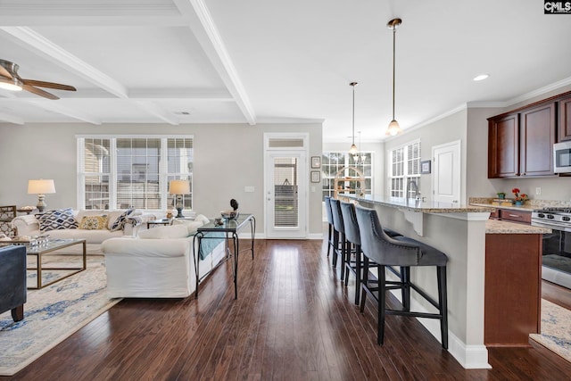 kitchen with appliances with stainless steel finishes, open floor plan, healthy amount of natural light, a breakfast bar, and recessed lighting