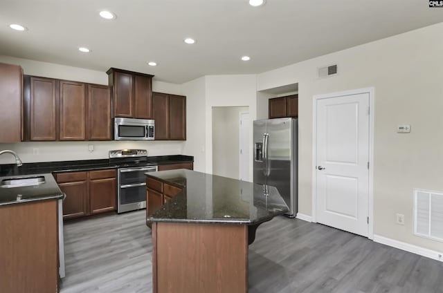 315 Merus Dr, Lexington, SC 29072 - kitchen with stainless steel appliances, a sink, a kitchen island, light wood-type flooring, and dark stone counters