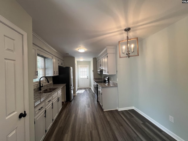 kitchen featuring a sink, stainless steel appliances, baseboards, a chandelier, and dark wood finished floors