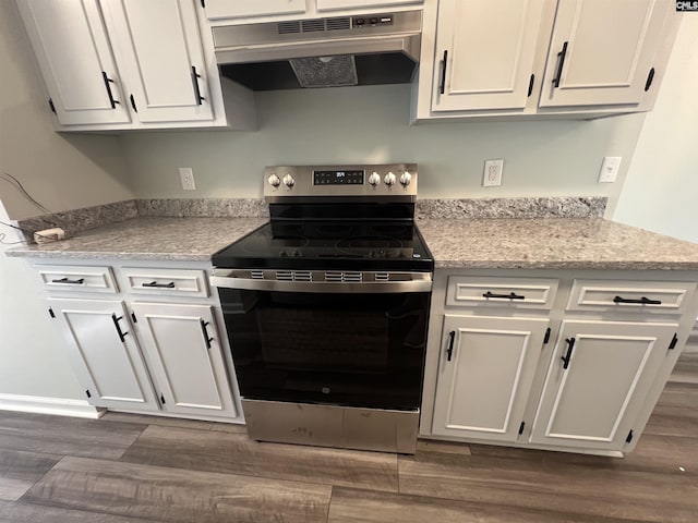 kitchen featuring electric stove, under cabinet range hood, dark wood-style flooring, and white cabinetry