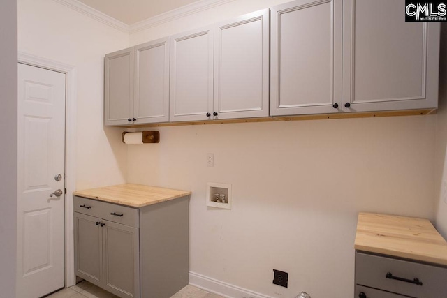 washroom with cabinet space, hookup for a washing machine, crown molding, and baseboards