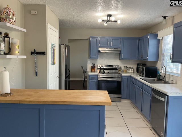 kitchen featuring stainless steel appliances, blue cabinets, a sink, under cabinet range hood, and a textured ceiling
