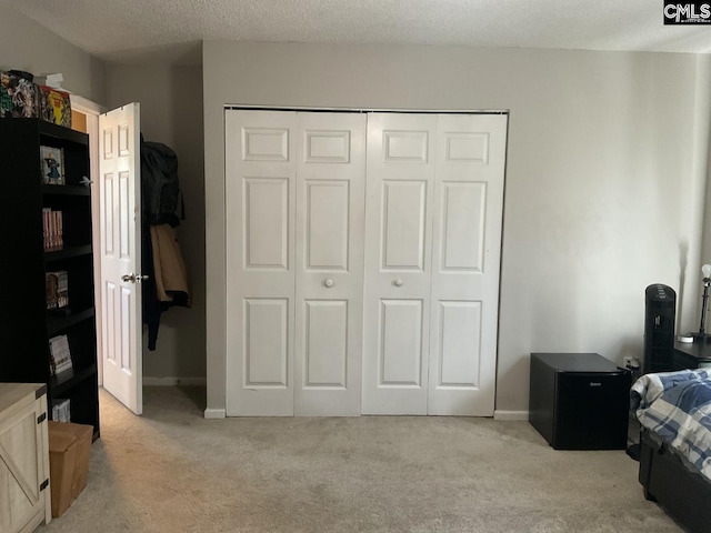 bedroom featuring light carpet, a closet, a textured ceiling, and baseboards