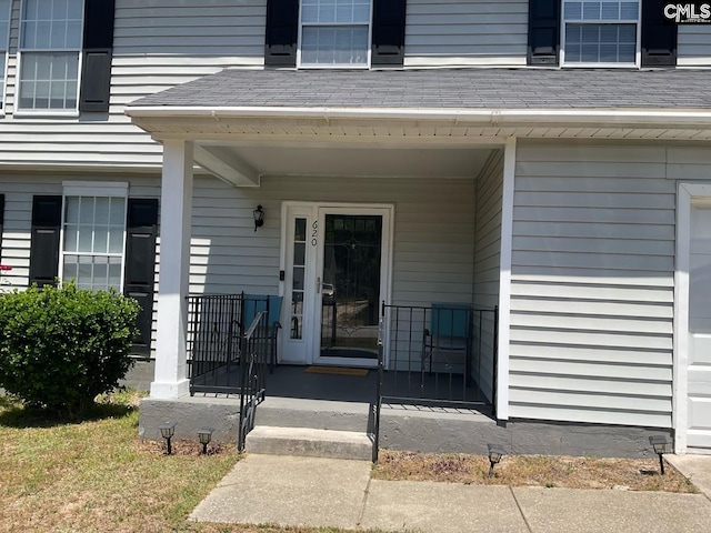 entrance to property featuring a porch and a shingled roof