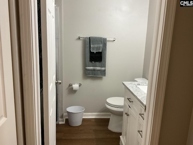 bathroom with wood finished floors, vanity, toilet, and baseboards