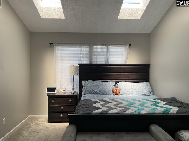 carpeted bedroom with a skylight, a textured ceiling, baseboards, and multiple windows