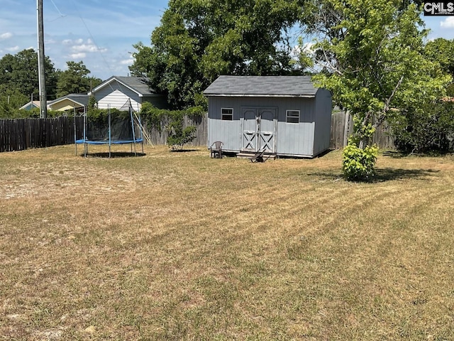 view of yard with a trampoline, a storage unit, and an outbuilding