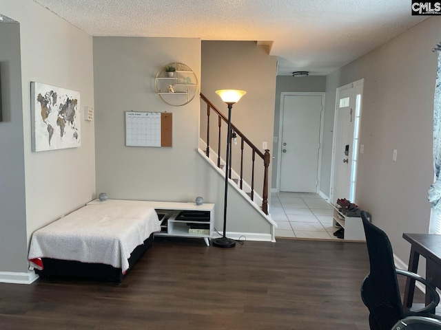 entryway featuring wood finished floors, stairs, baseboards, and a textured ceiling