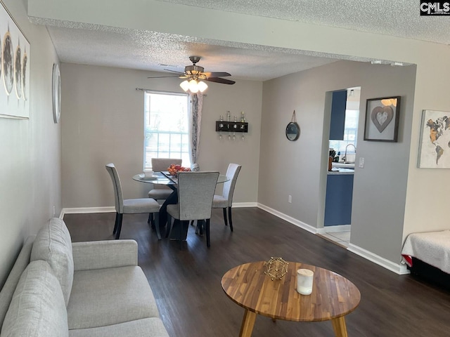 dining area featuring a textured ceiling, dark wood finished floors, baseboards, and ceiling fan