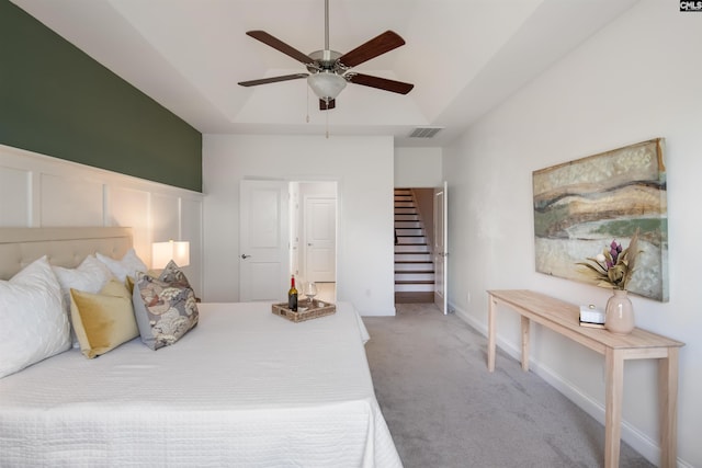bedroom with carpet flooring, a raised ceiling, and a ceiling fan