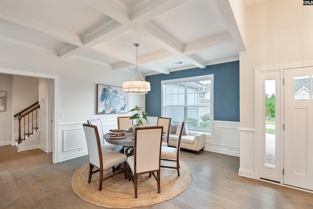 dining space featuring beam ceiling, coffered ceiling, stairway, wood finished floors, and a decorative wall
